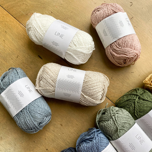 Pastel balls of Sandnes Garn Line yarn arranged on a wooden surface.