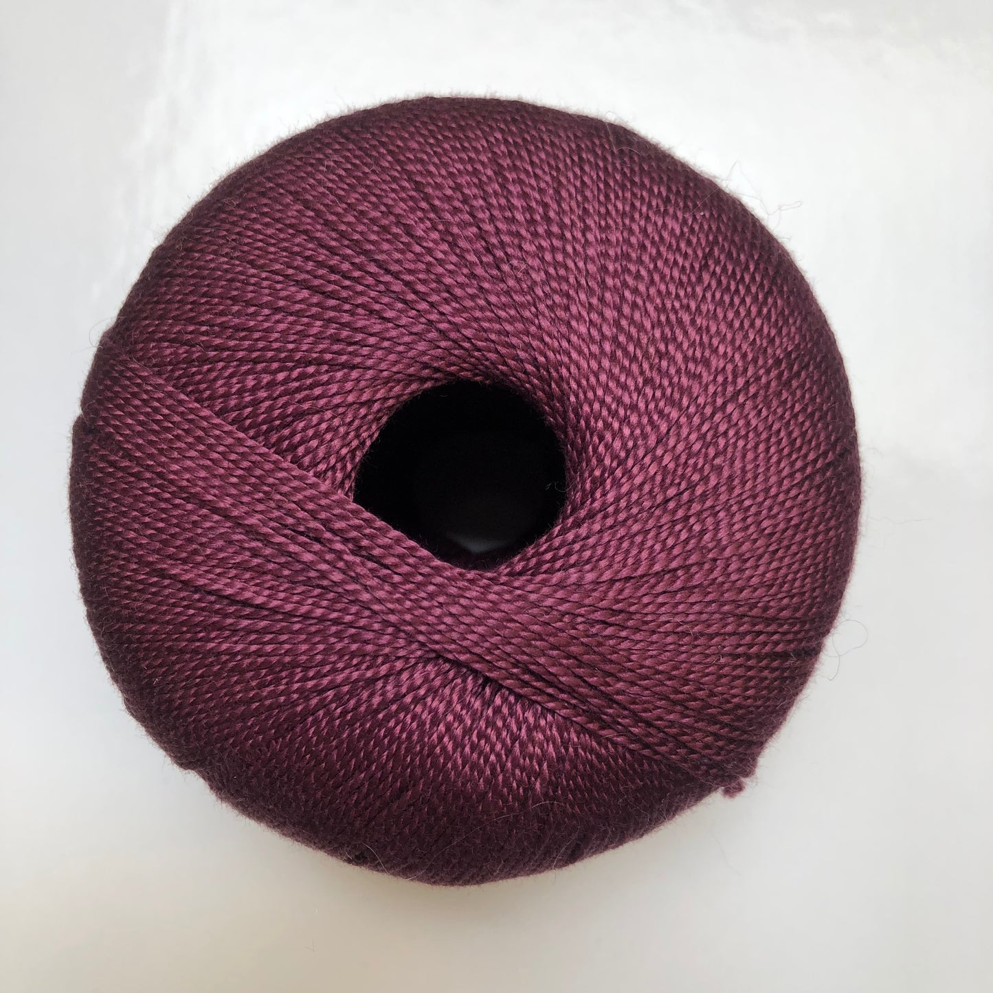 Ball of burgundy Isager Bomuld yarn.