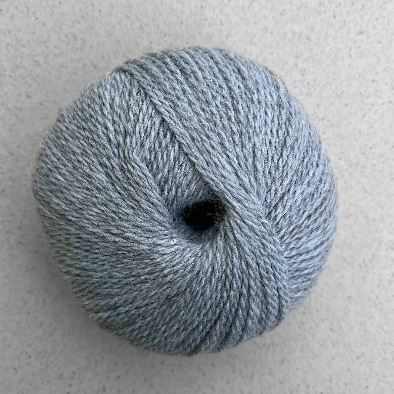 Ball of heathered blue gray Pascuali Balayage yarn.