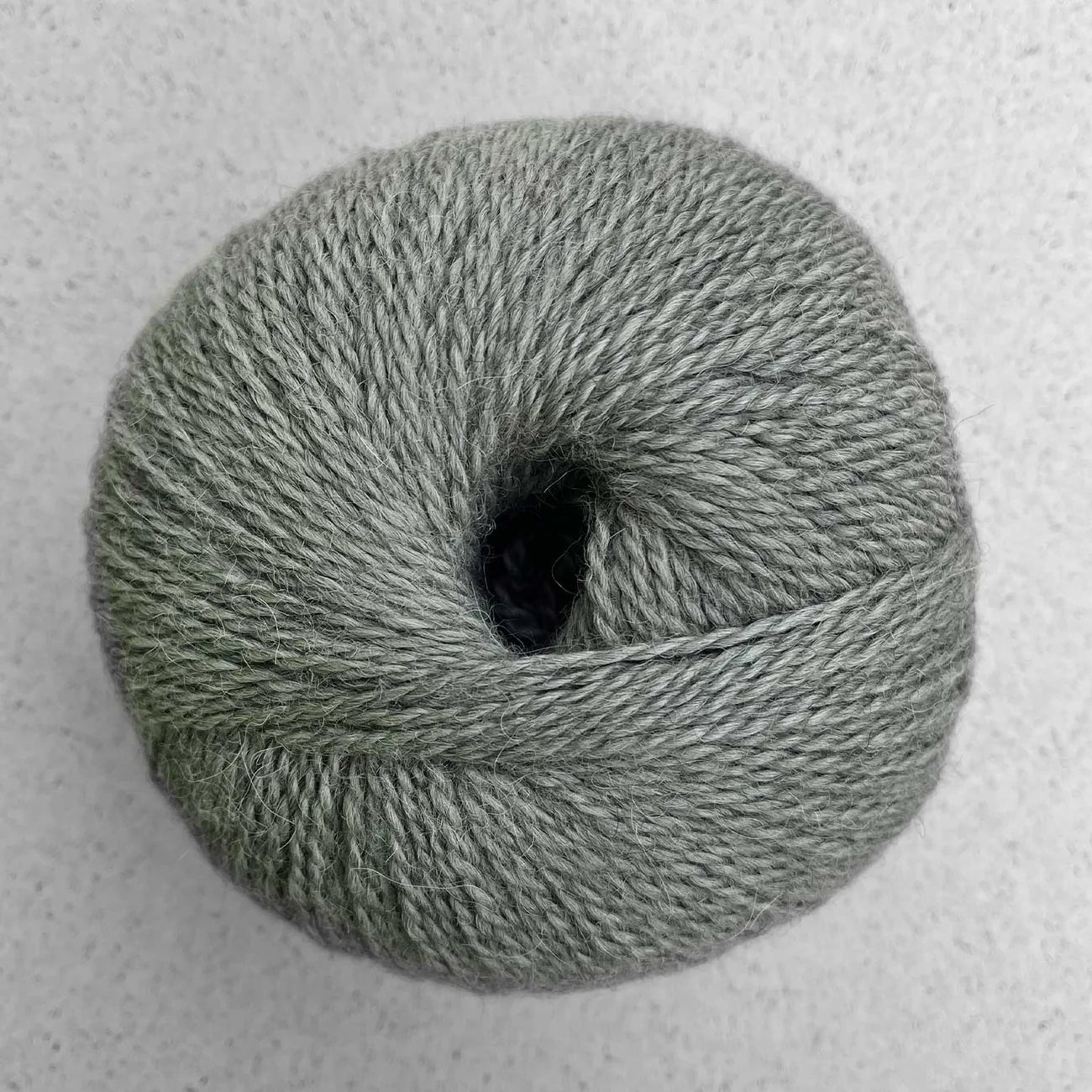Ball of heathered sage green Pascuali Balayage yarn.