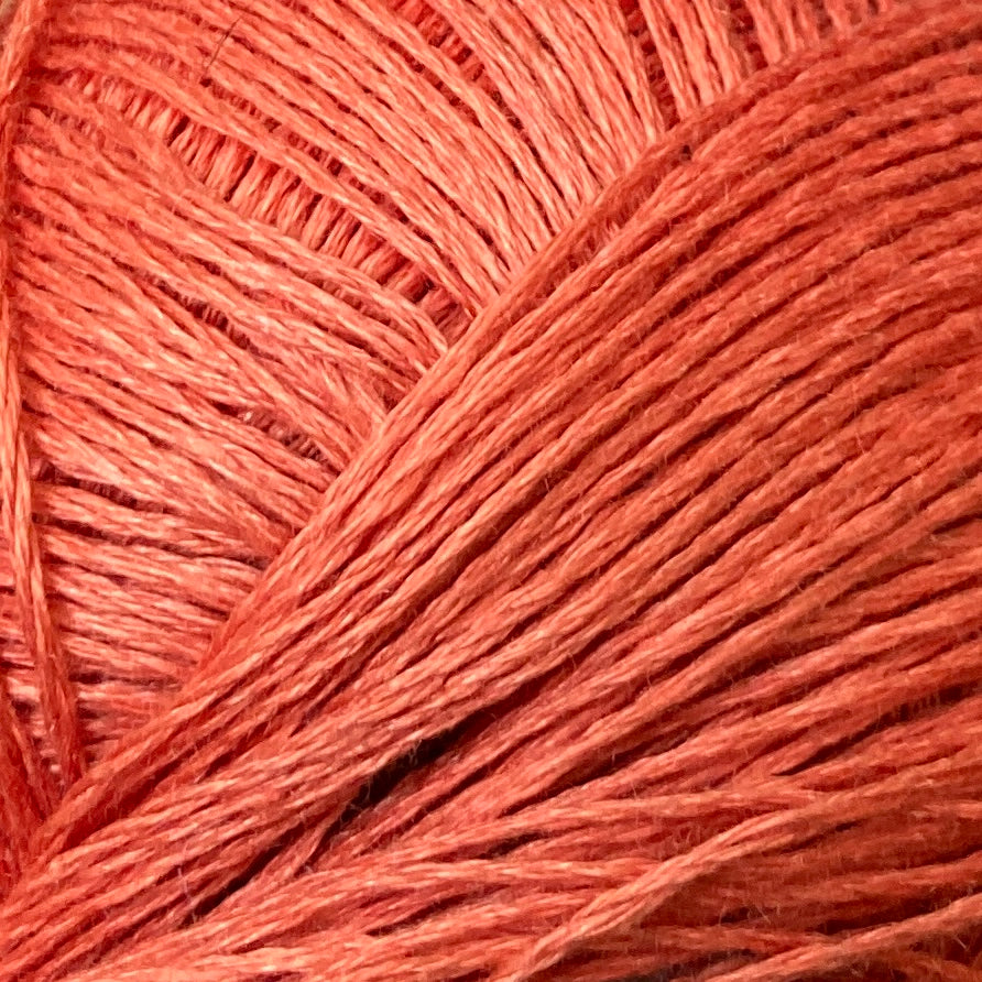 Close up on a coral orange ball of Katia Lino 100% yarn.