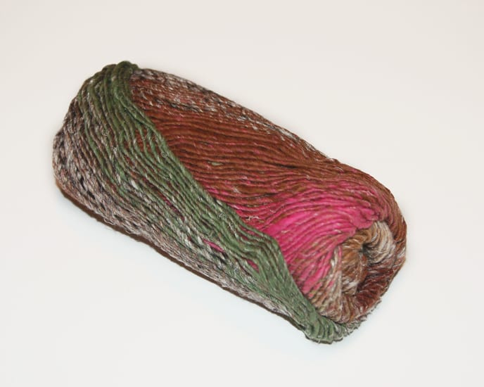 A skein of self-striping yarn with green, brown and pink showing.