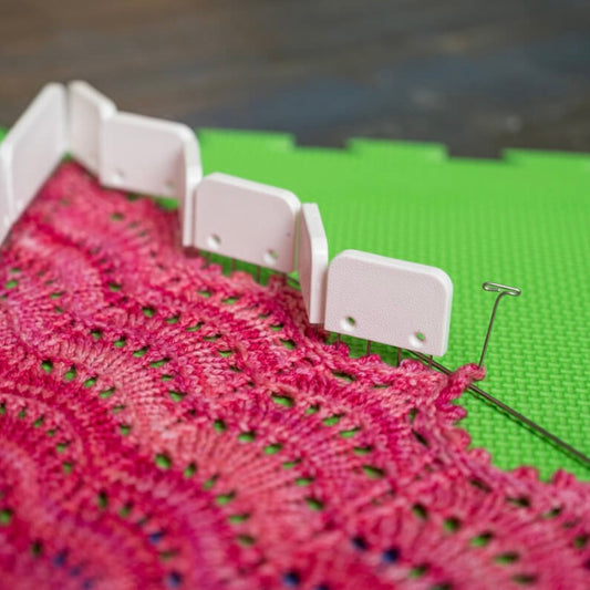 Knit Blockers pinning the edge of a pink handknit lace shawl.