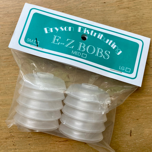 Clear package of round plastic bobbins on a wooden surface.