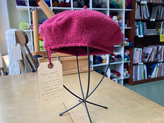 A raspberry beret on a hat stand, on display at the Hillsborough Yarn Shop.