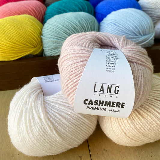 Colorful balls of Lang Cashmere Premium yarn on a wooden surface.