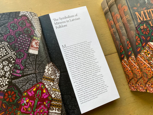 Maruta Grasmane’s Mittens of Latvia book, lying open to a page showing text and colorful mittens.