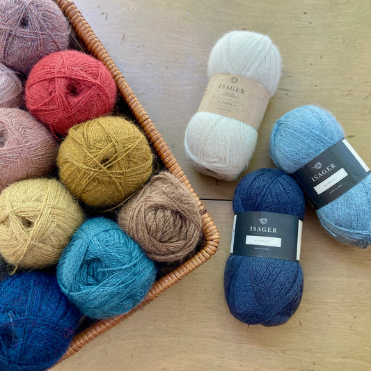 Balls of Isager Alpaca 1 yarn in a basket on a wooden surface.