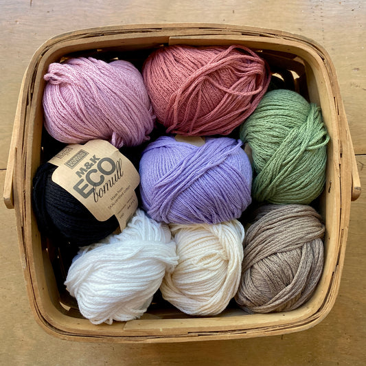 Square basket filled with colorful balls of M&K Eco Bomull yarn.