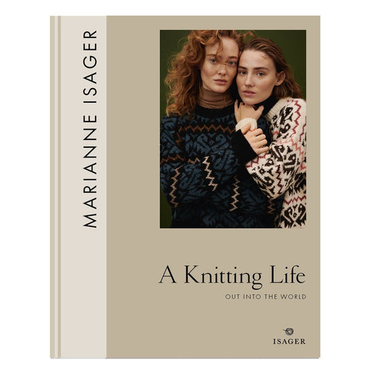 Book cover of A Knitting Life 2 - Out Into the World by Marianne Isager, featuring an image of two women modeling the sweater pattern 'Pelican' with an allover color-work motif.