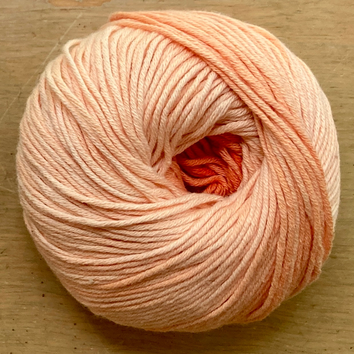 Ball of Katia Degrade yarn in shades of light orange.