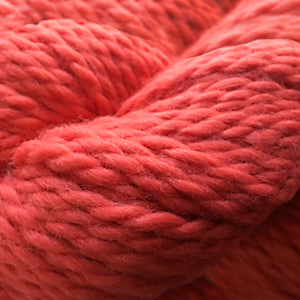 Close up on a skein of poppy red Cascade Baby Alpaca Chunky yarn.