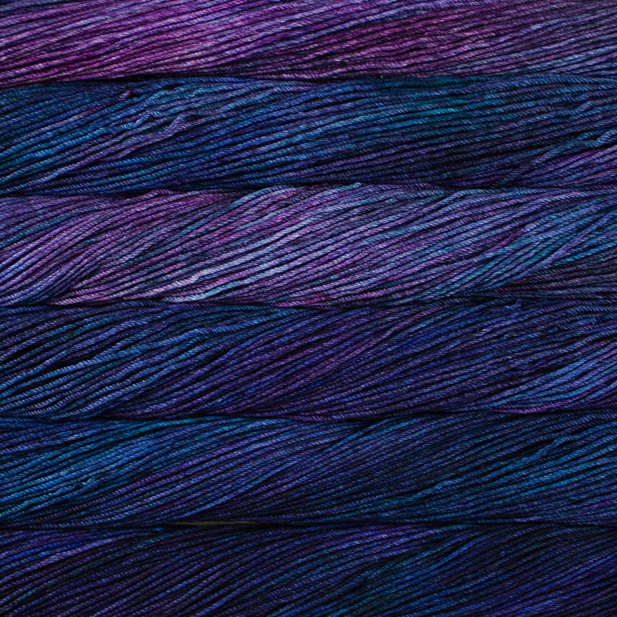 Skein of variegated blue and purple Malabrigo Caprino yarn.