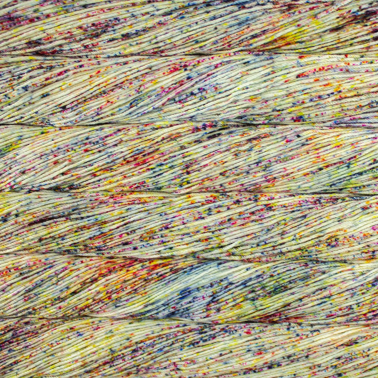 Skein of speckled white, orange, yellow and blue Malabrigo Caprino yarn.