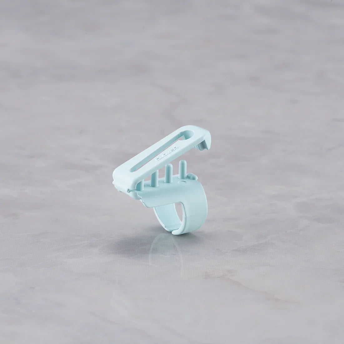 Light blue Clover yarn guide tool on a gray surface.