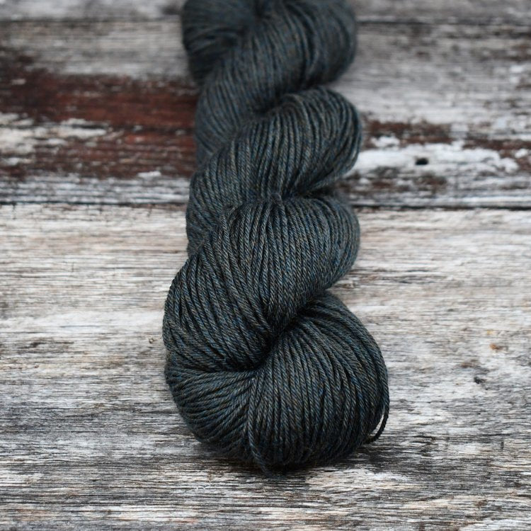Dark greenish gray skein of CoopKnits Socks Yeah! yarn on a wooden