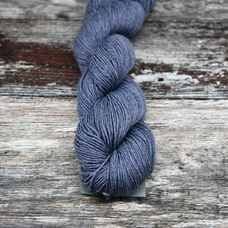 Medium gray-blue skein of CoopKnits Socks Yeah! yarn on a wooden