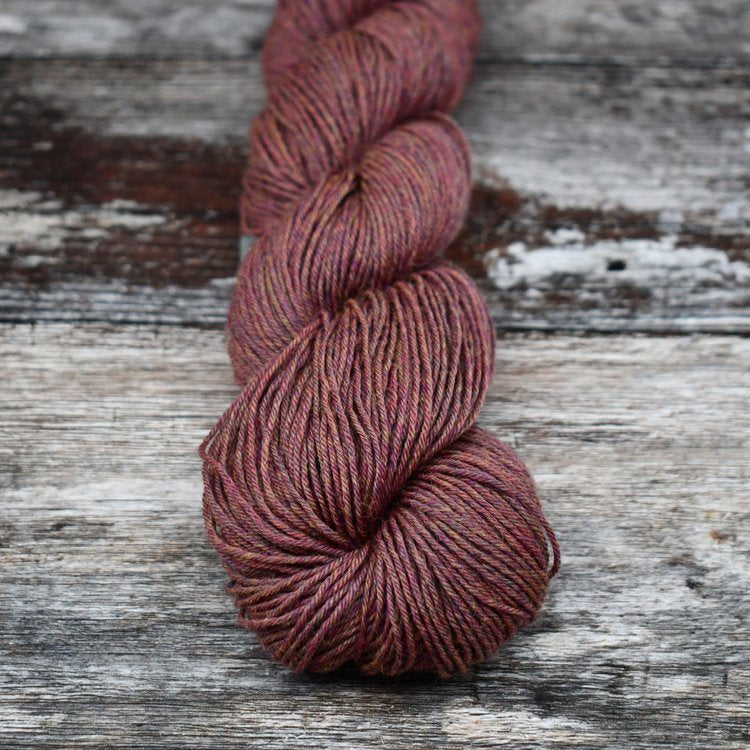 Maroon with orange flecks skein of CoopKnits Socks Yeah! yarn on a wooden