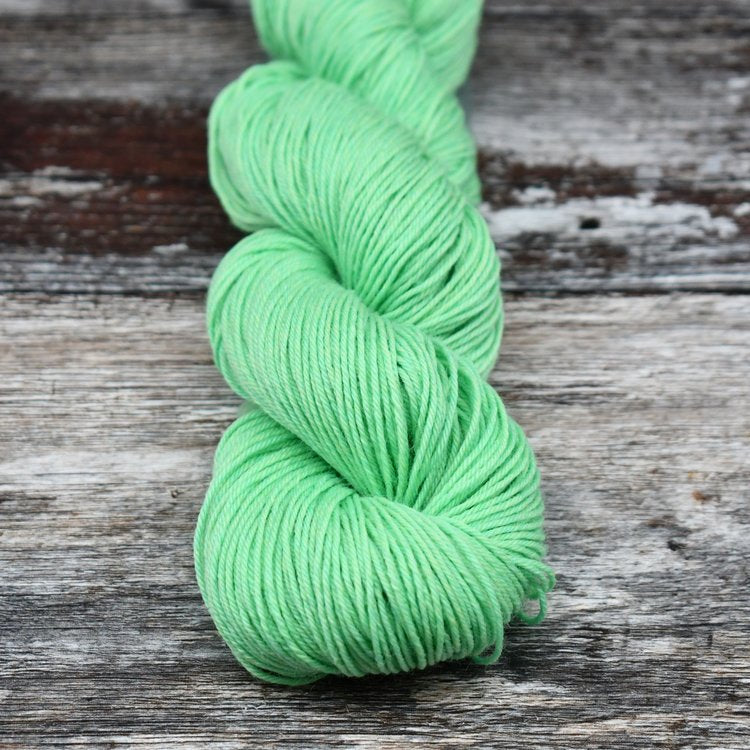 Bright mint green skein of CoopKnits Socks Yeah! yarn on a wooden
