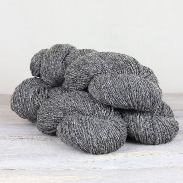 Three skeins of medium gray Fibre Co. Arranmore Light yarn.