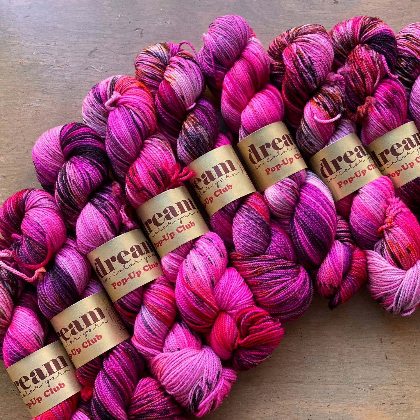 Variegated neon pink and burgundy skeins of Dream in Color Smooshy Cashmere yarn.