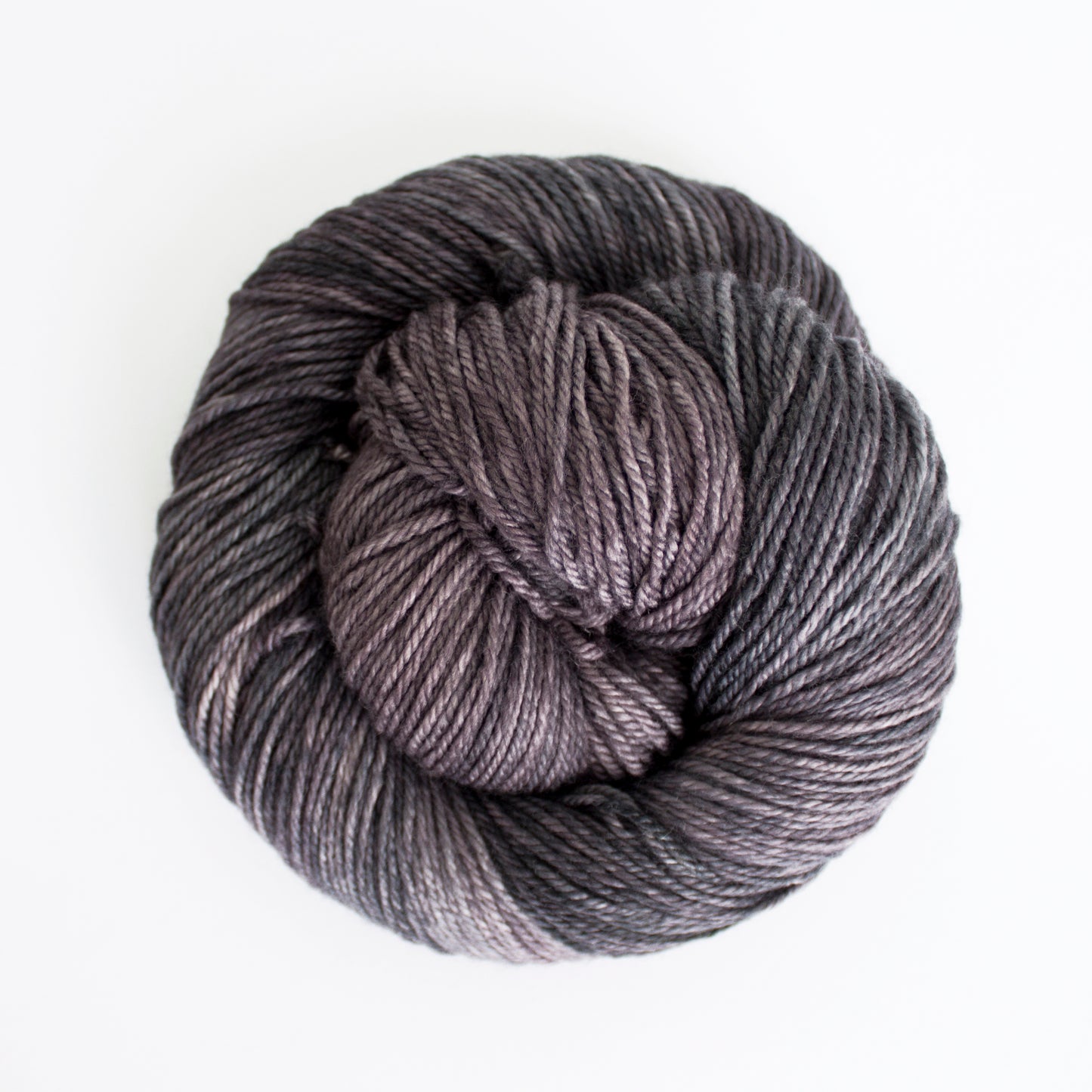 Skein of variegated gray and purple Malabrigo Finito yarn.
