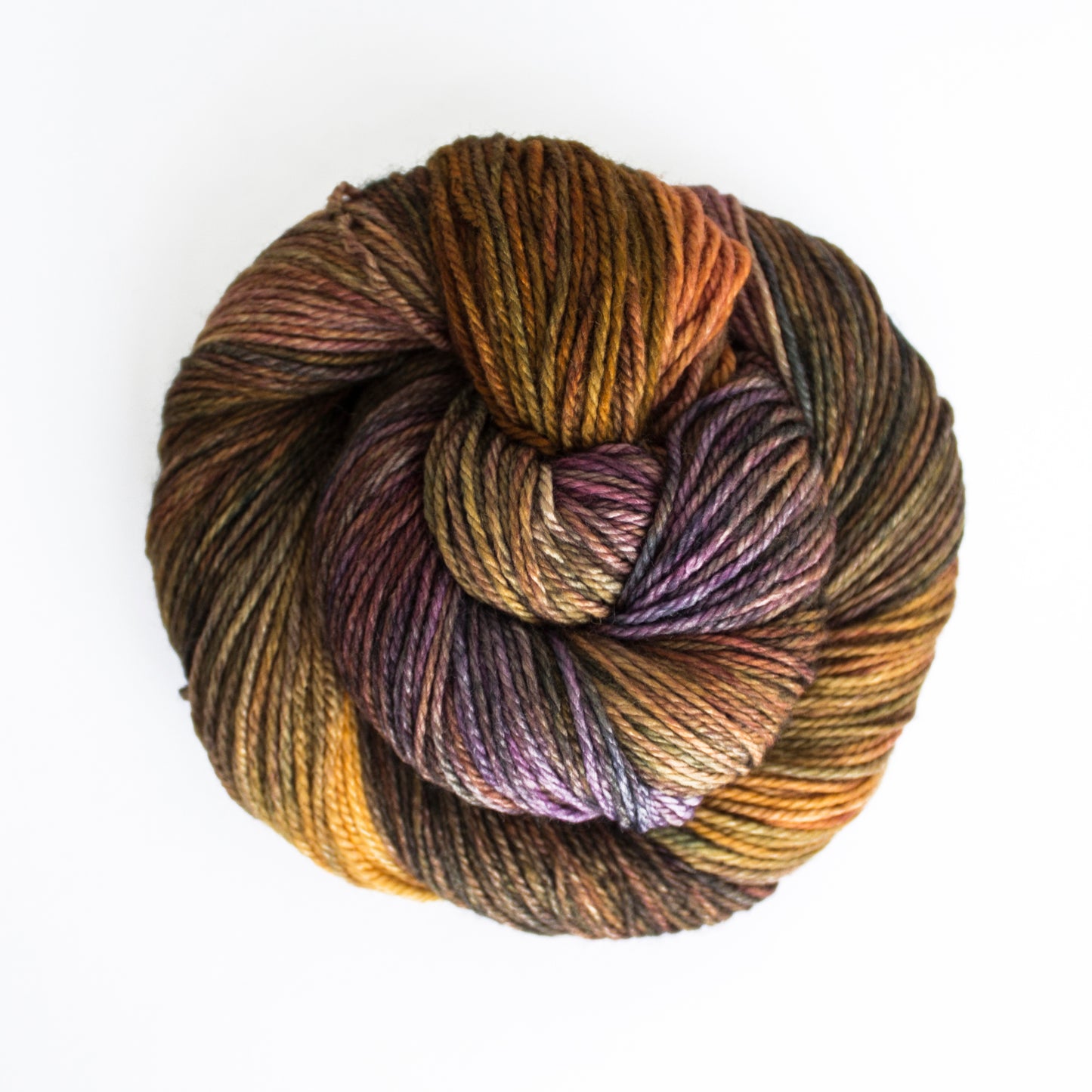 Skein of variegated brown, orange, and moss green Malabrigo Finito yarn.
