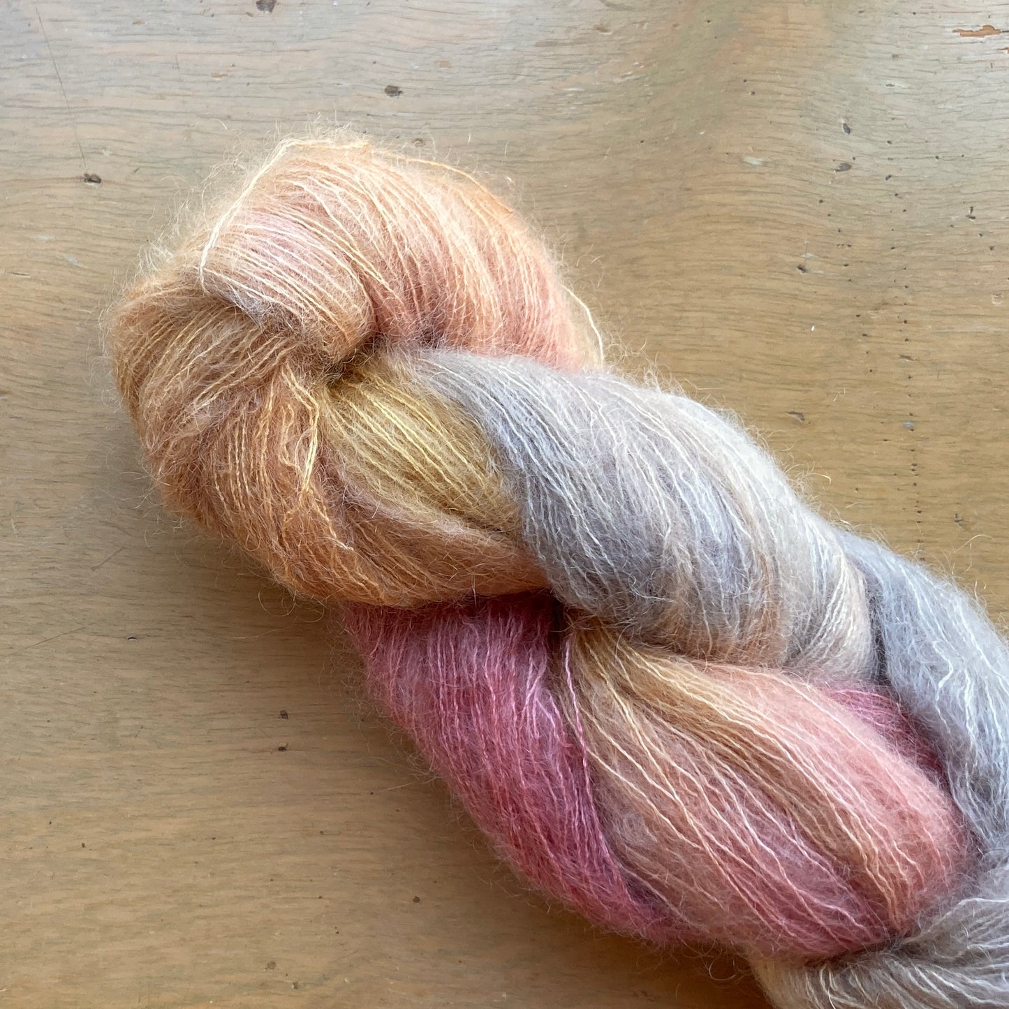 Peach, pink, gray and wheat skein of Fleece Artist / Hand Maiden Superkid Silk yarn, colorway Fire Opal