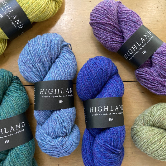 Colorful skeins of Harrisville Highland yarn arranged on a wooden surface at Hillsborough Yarn Shop