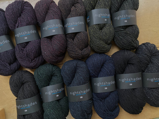 Harrisville nightshades in shades of black, yarn arranged on a wooden surface.