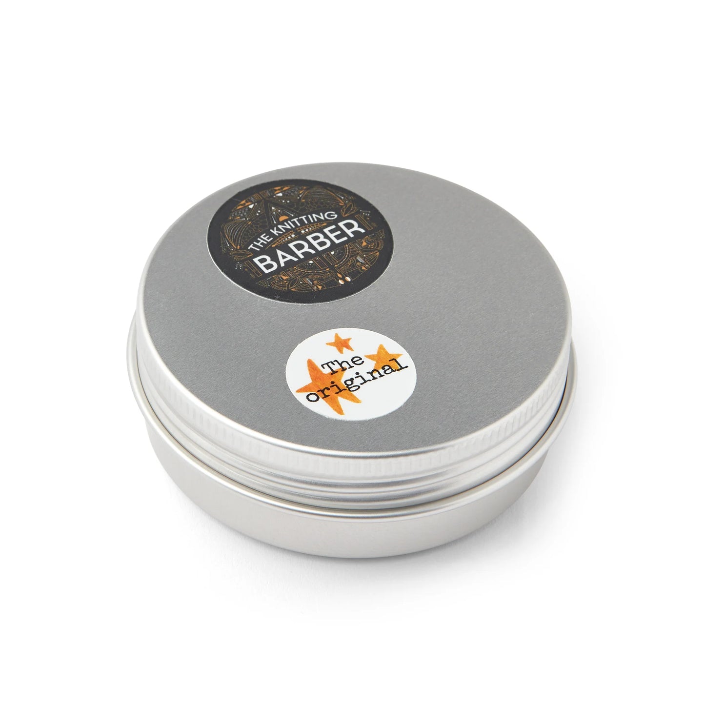 Round silver tin with The Knitting Barber sticker on top.