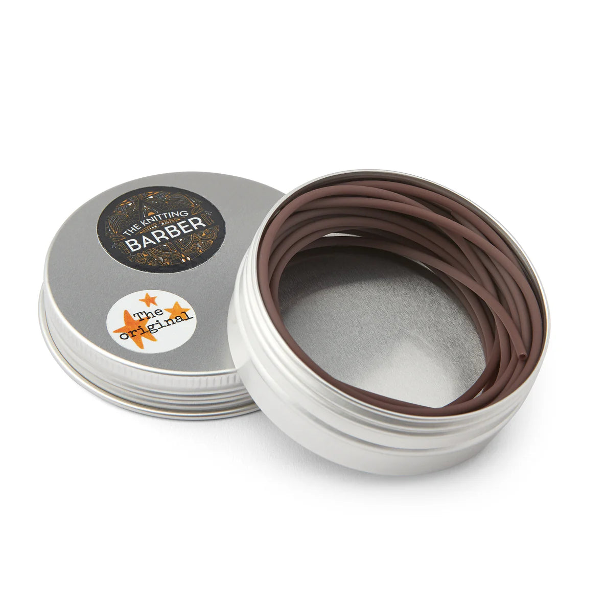 Round silver tin lying open beside its lid, showing brown Knitting Barber Cords coiled inside.