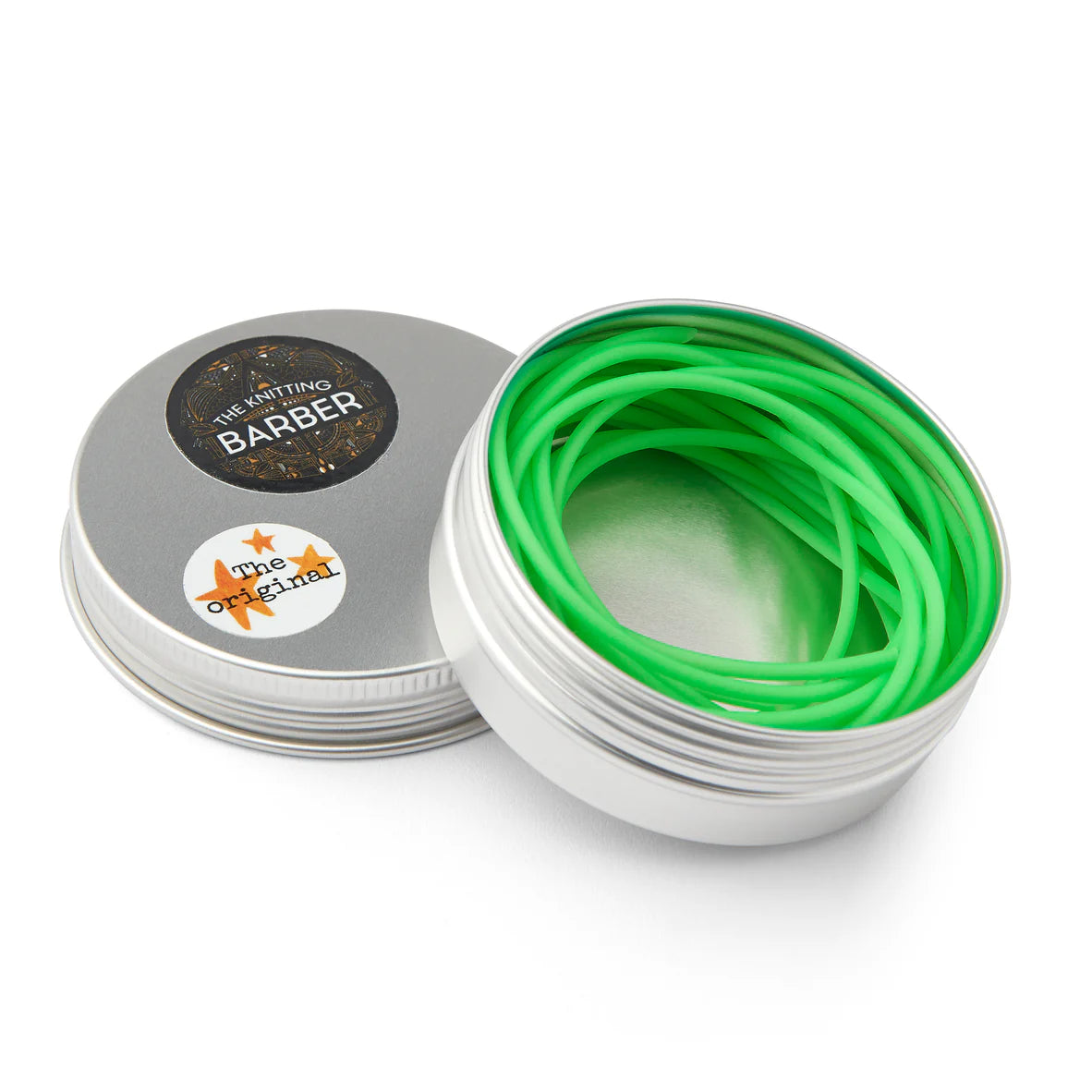 Round silver tin lying open beside its lid, showing green Knitting Barber Cords coiled inside.