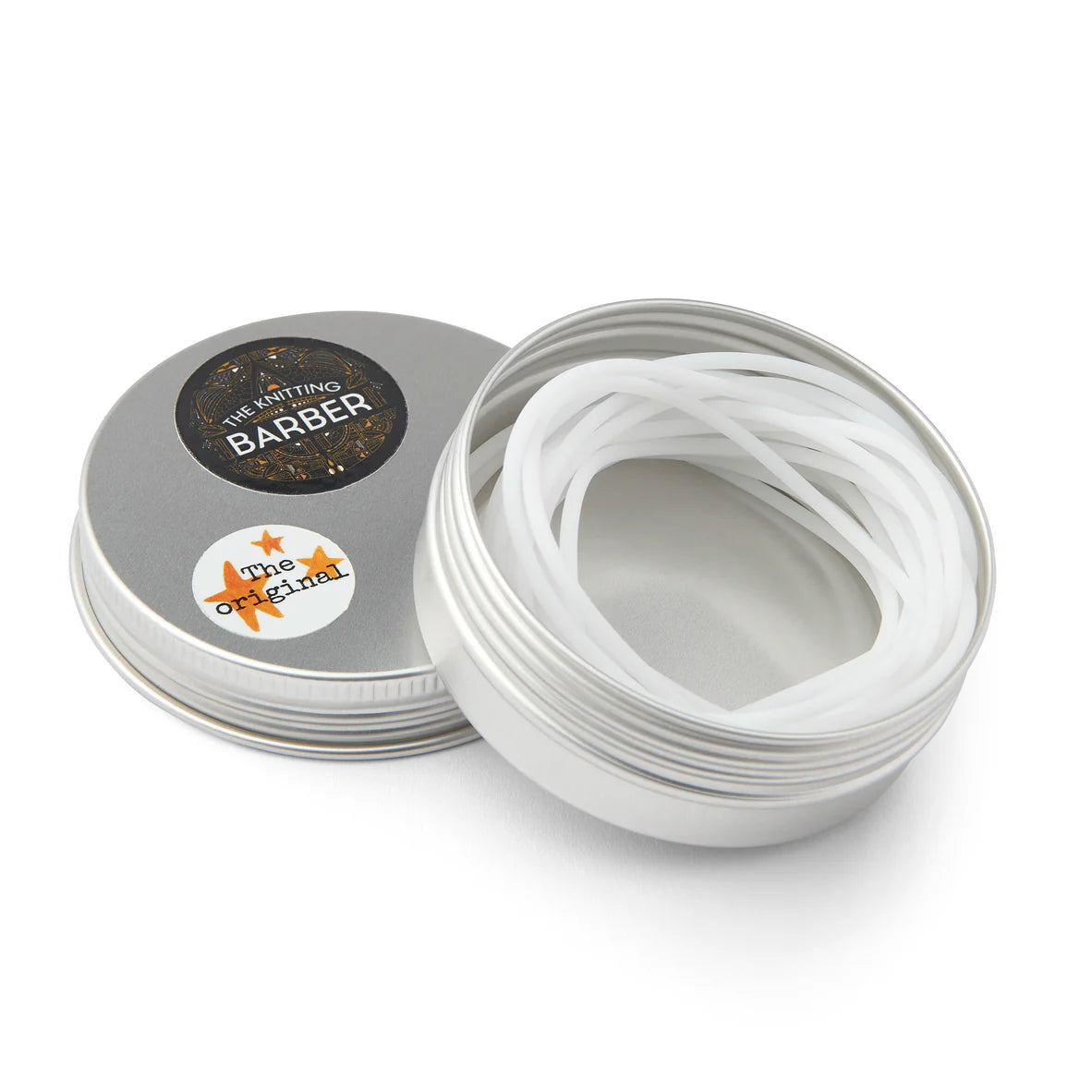 Round silver tin lying open beside its lid, showing white Knitting Barber Cords coiled inside.