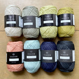 Isager Japansk Bomuld yarn arranged on a wooden surface.