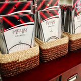 Small rectangular baskets holding Knitter’s Pride Karbonz circular needles, sitting on top of a dark burgundy library card catalog.