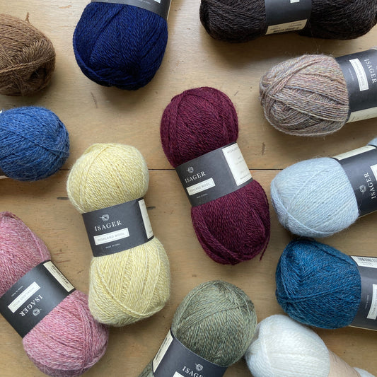 Colorful balls of Isager Highland Wool on a wooden surface in front of a window - yarn for sale at Hillsborough Yarn Shop, NC, USA