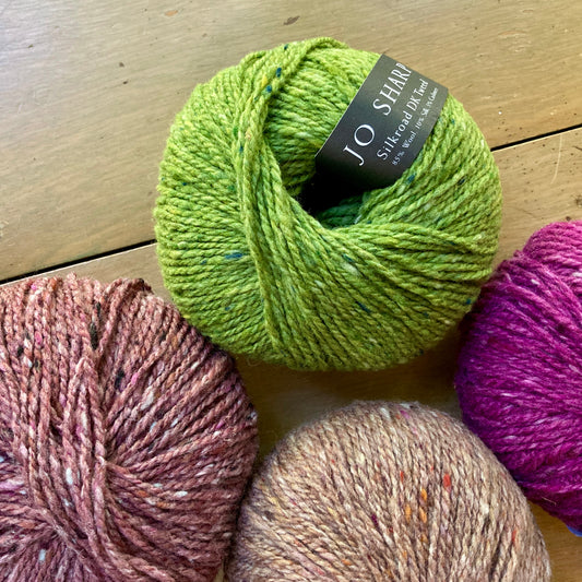 Green, pink, and beige balls of Jo Sharp Silkroad DK Tweed yarn.