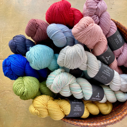 Basket of colorful hand dyed skeins of Julie Asselin Leizu Fingering Non Traitée yarn on display at Hillsborough Yarn Shop