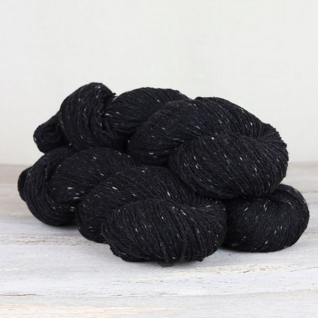Three skeins of black Fibre Co. Arranmore Light yarn.