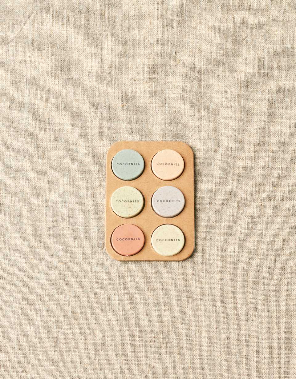 Round pastel magnets on a light gray surface.
