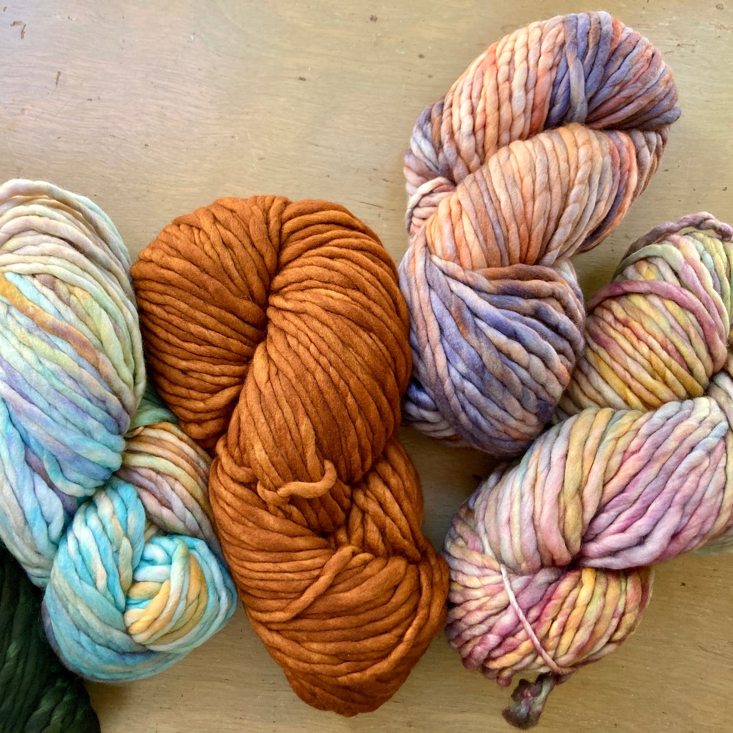 Four skeins of Malabrigo Rasta yarn arranged on a wooden surface.