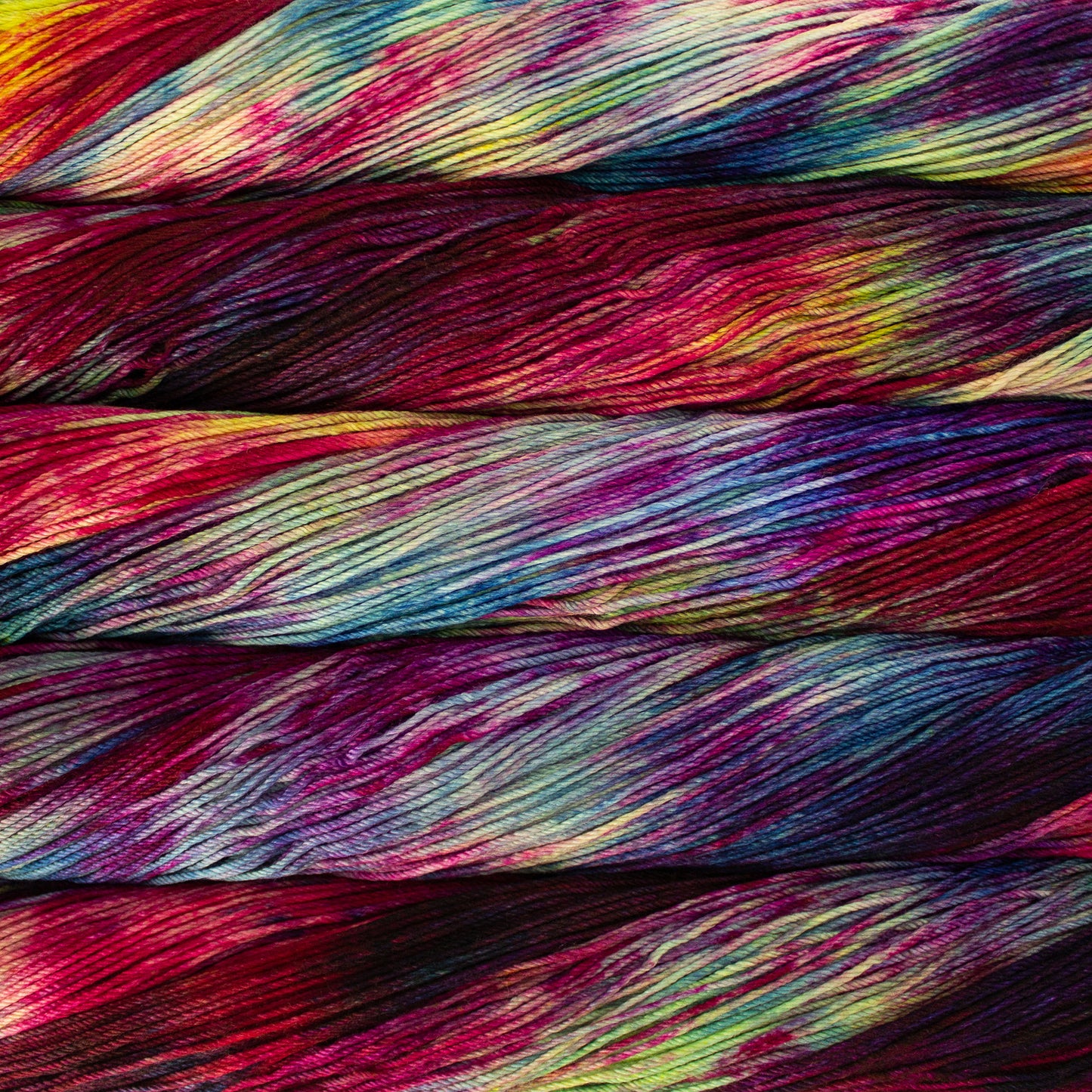 Skein of variegated red, blue, yellow, and purple Malabrigo Arroyo yarn.