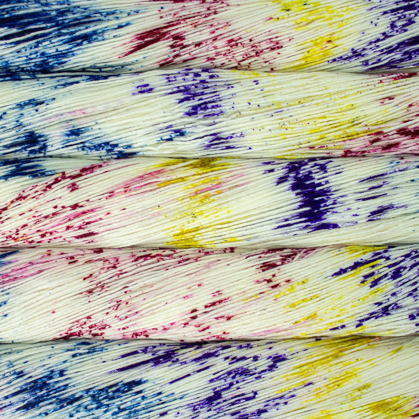 Skeins of yarn with a white base speckled with blue, red, and yellow - Ultimate Sock by Malabrigo in Unicorn Bark
