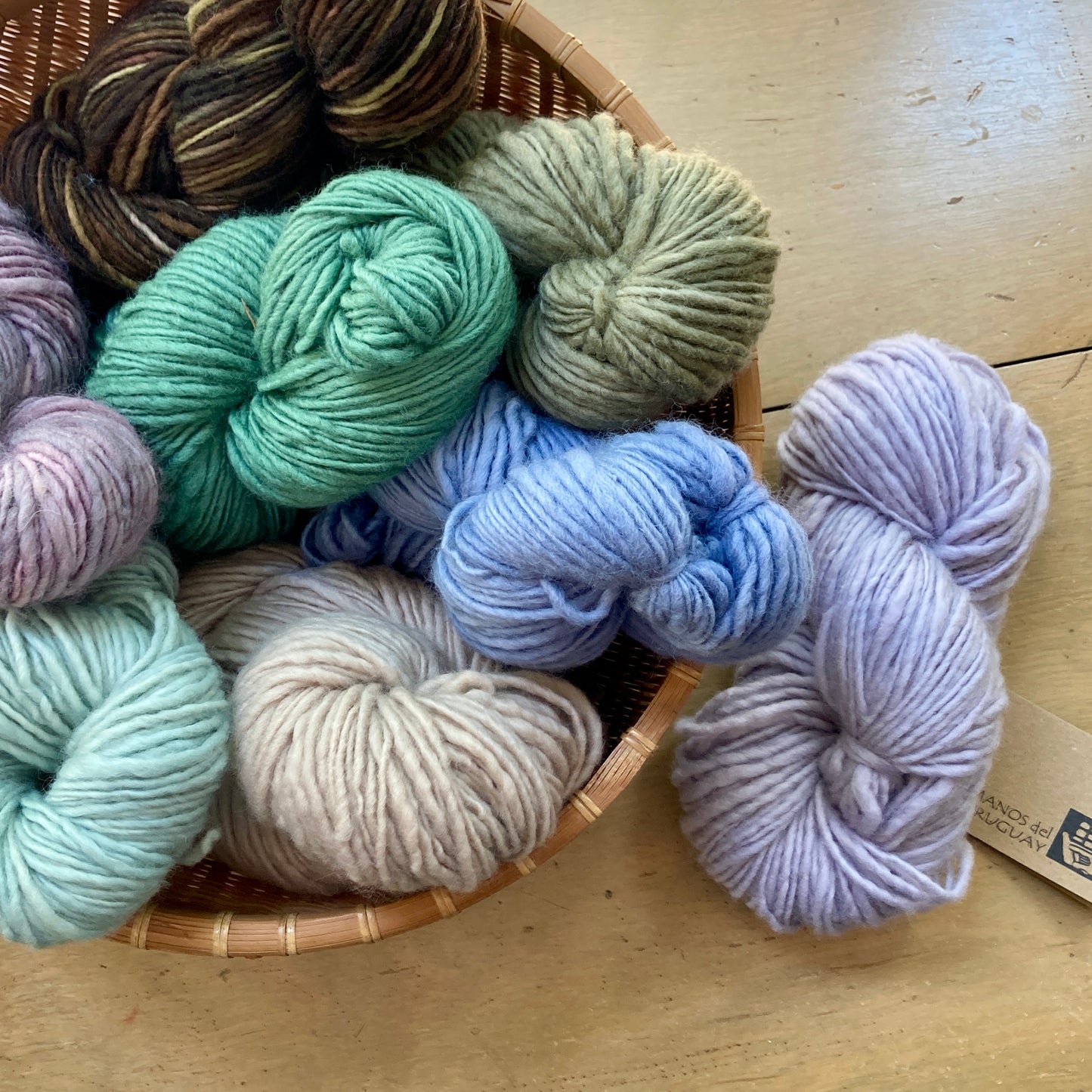 Basket of Manos del Uruguay Wool Clásica yarn in muted colors.