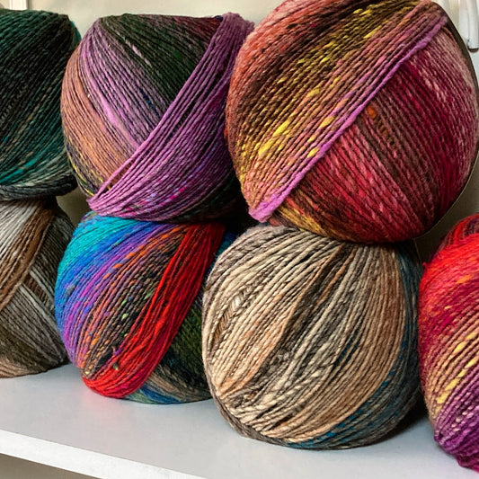 Colorful balls of self striping Noro Ito yarn arranged on a shelf at Hillsborough Yarn Shop.