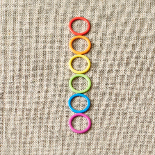 Colorful ring stitch markers on a light gray background.