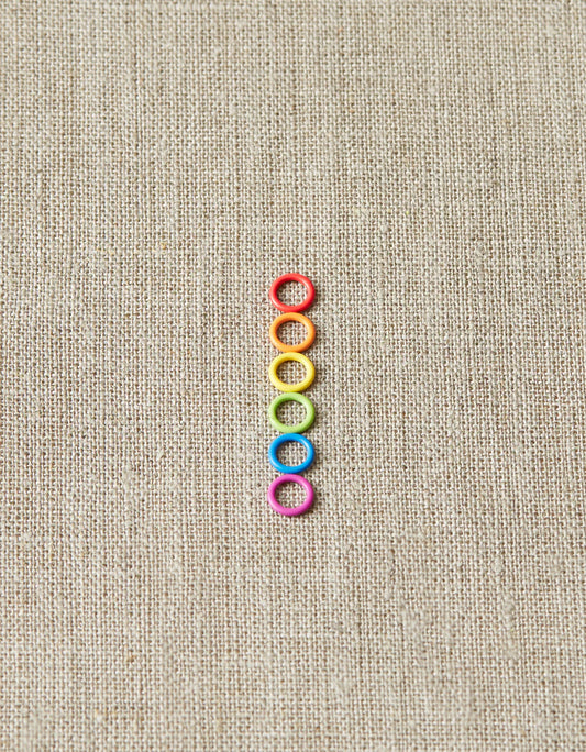 Colorful ring stitch markers on a light gray background.