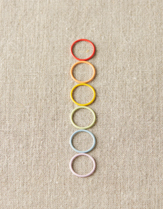 Rainbow of pastel round markers on a gray background.