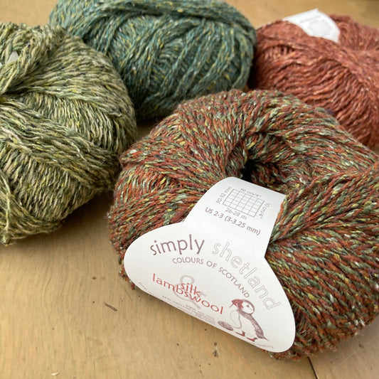 Simply Shetland Silk & Lambswool yarn in tweedy earth tones arranged on a wooden surface at Hillsborough Yarn Shop
